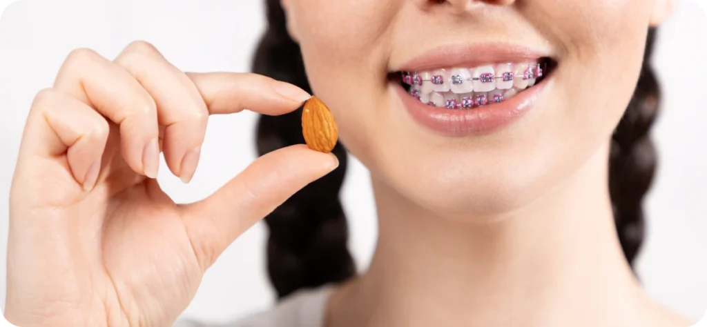 Femme portant un appareil orthodontique tenant une amande