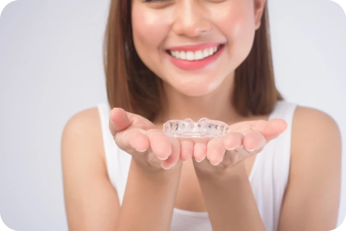 Patiente souriante tenant une gouttière de contention transparente