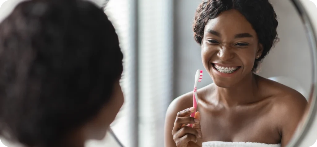 Femme portant un appareil orthodontique et tenant une brosse à dents