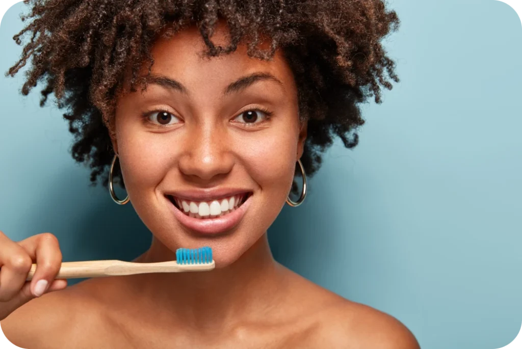 Femme souriante tenant une brosse à dents pour son hygiène bucco-dentaire