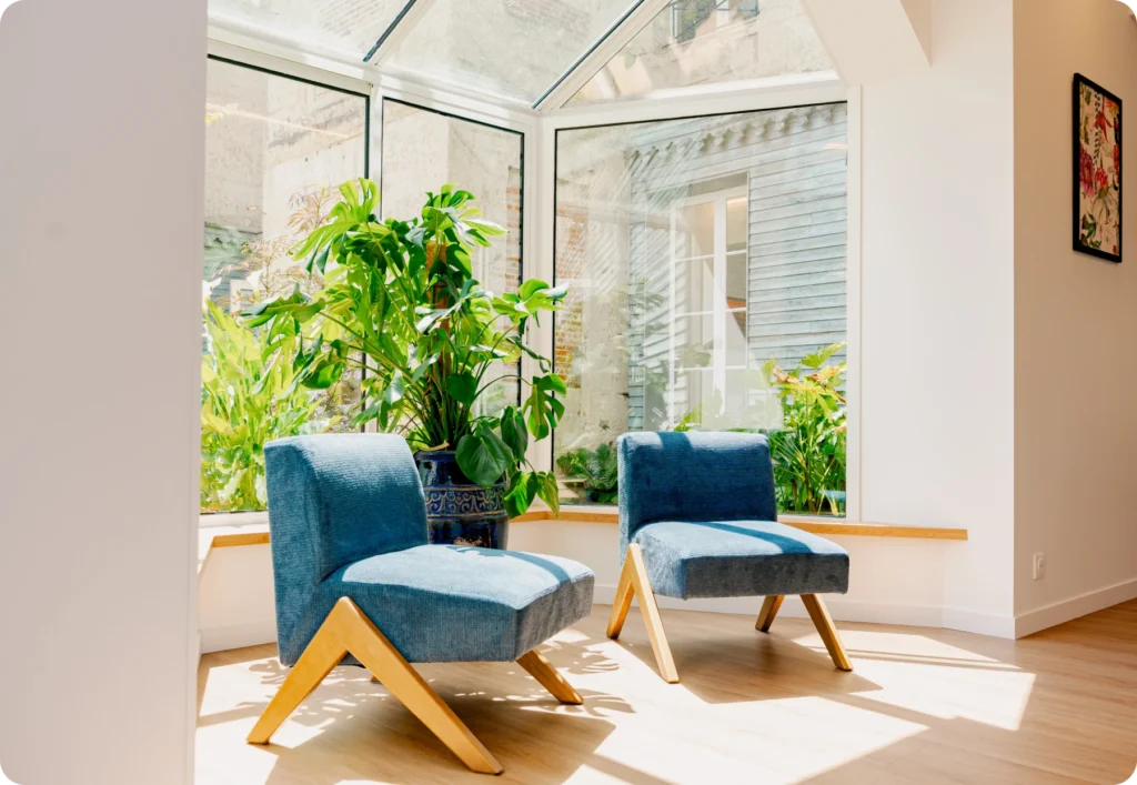Véranda avec fauteuils bleus et vue sur le jardin
