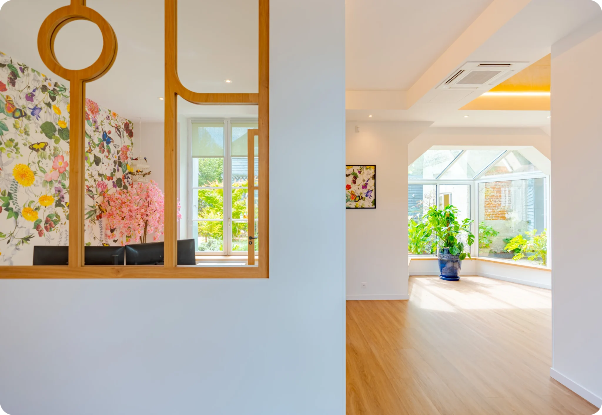 Couloir vitré en bois ouvrant sur la salle d'attente et le jardin du cabinet d'orthodontie des Drs Davy & Alam