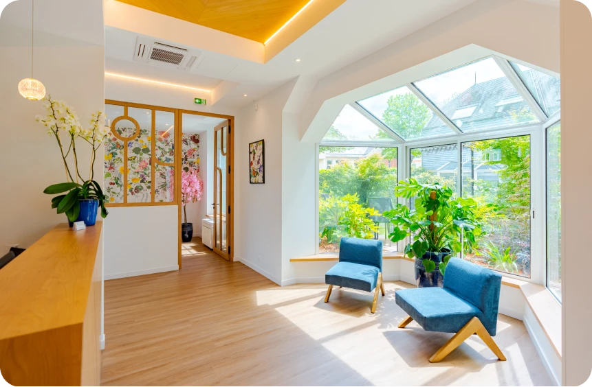 Salle d'attente lumineuse du cabinet d'orthodontie des Drs Davy & Alam avec fauteuils bleus et vue sur le jardin