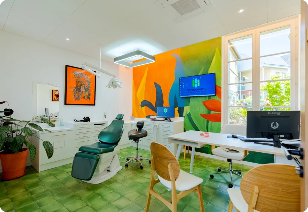 Salle de soins du cabinet d'orthodontie avec fauteuil dentaire et fresque murale tropicale