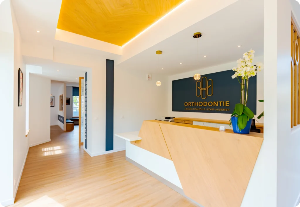 Vue d'ensemble de l'accueil et du couloir du cabinet d'orthodontie avec enseigne murale