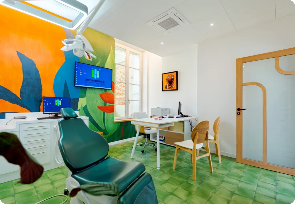 Salle de soins avec fresque tropicale colorée et fauteuil de traitement vert