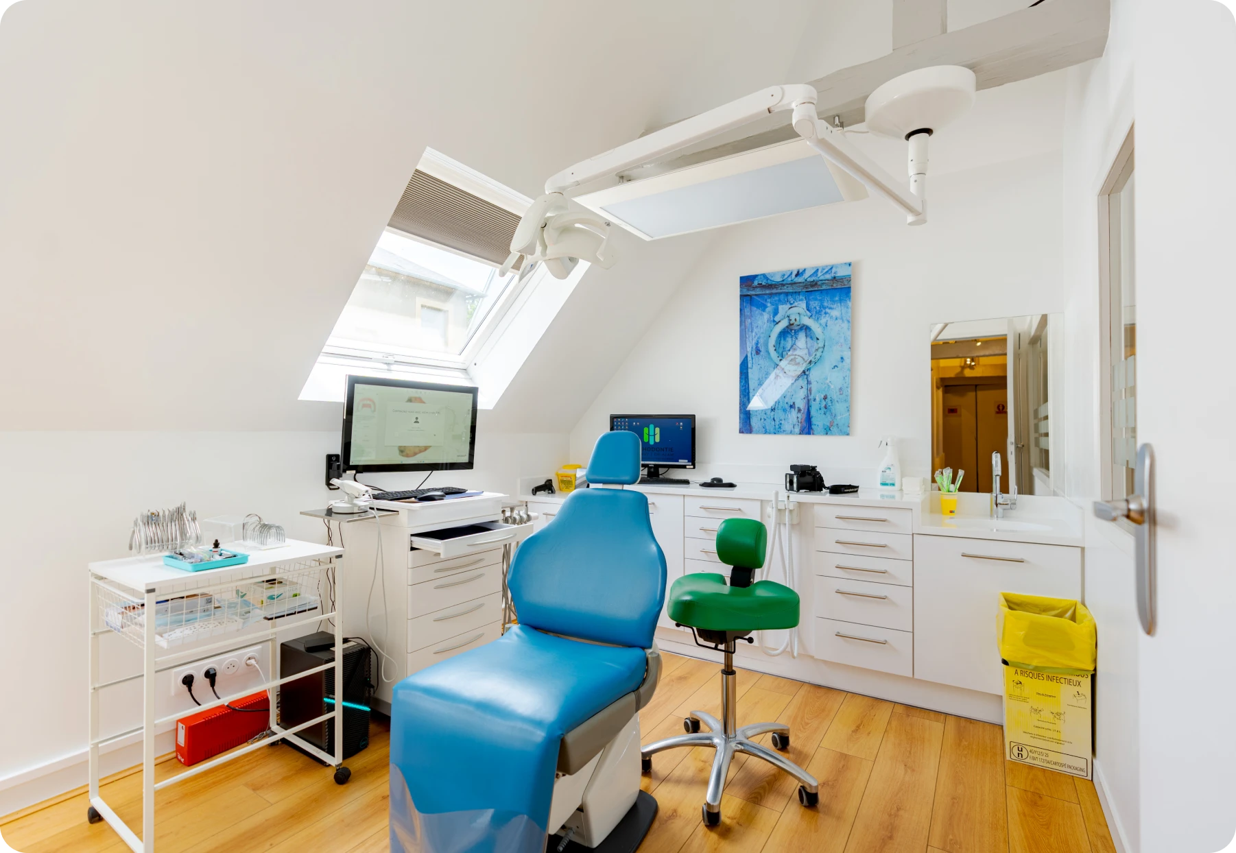 Salle de soins sous les combles avec fauteuil bleu et écran