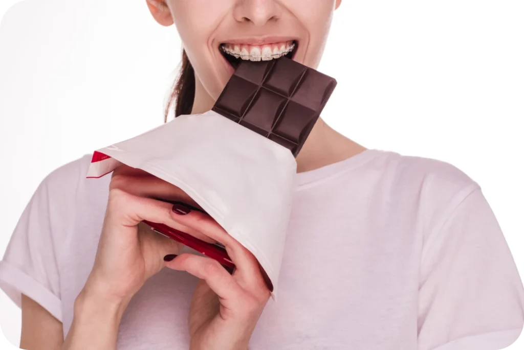 Femme portant un appareil orthodontique tenant une tablette de chocolat