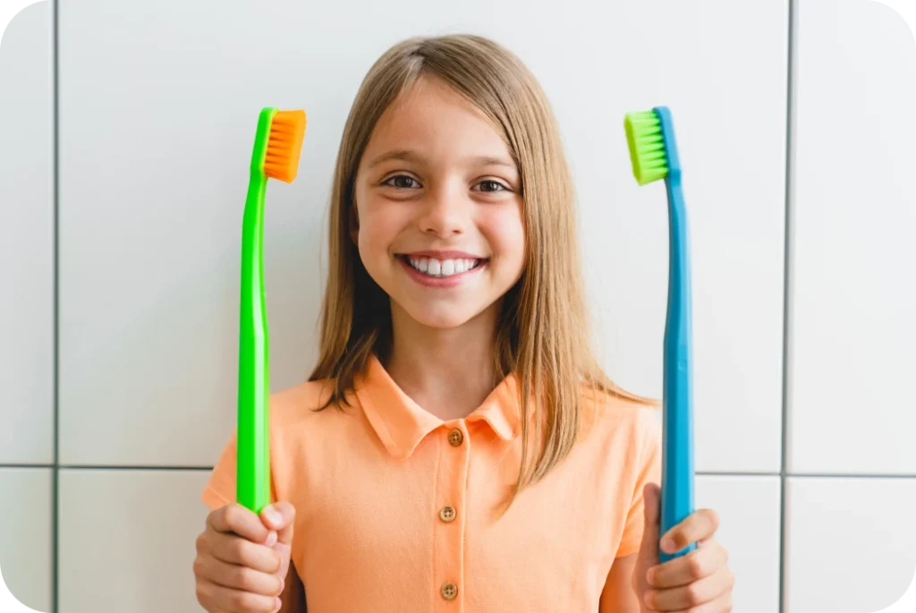 Enfant souriante tenant deux brosses à dents