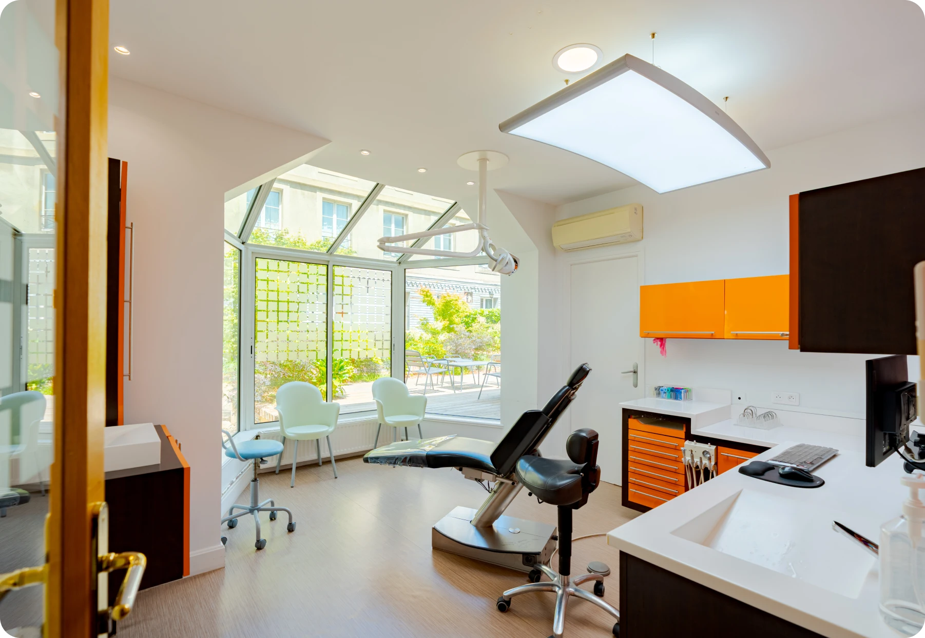 Salle de soins avec caissons orange, fauteuil de traitement et vue sur le jardin